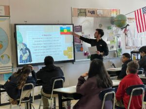 A participant of the ChileMass Teachers program teaches a class about the Mapuche people to students in a Massachusetts classroom, as part of the Boston immersion experience.