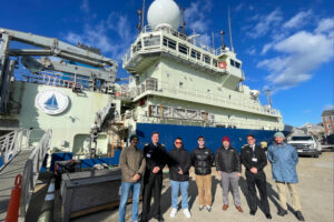 Chilean Navy innovation delegation in Boston during a visit to the Woods Hole Oceanographic Institution (WHOI), standing in front of a research vessel as part of a strategic immersion in maritime and ocean innovation.